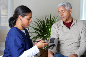 caregiver checking blood pressure of the old man