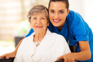 smiling caregiver assisting the old woman on the wheelchair